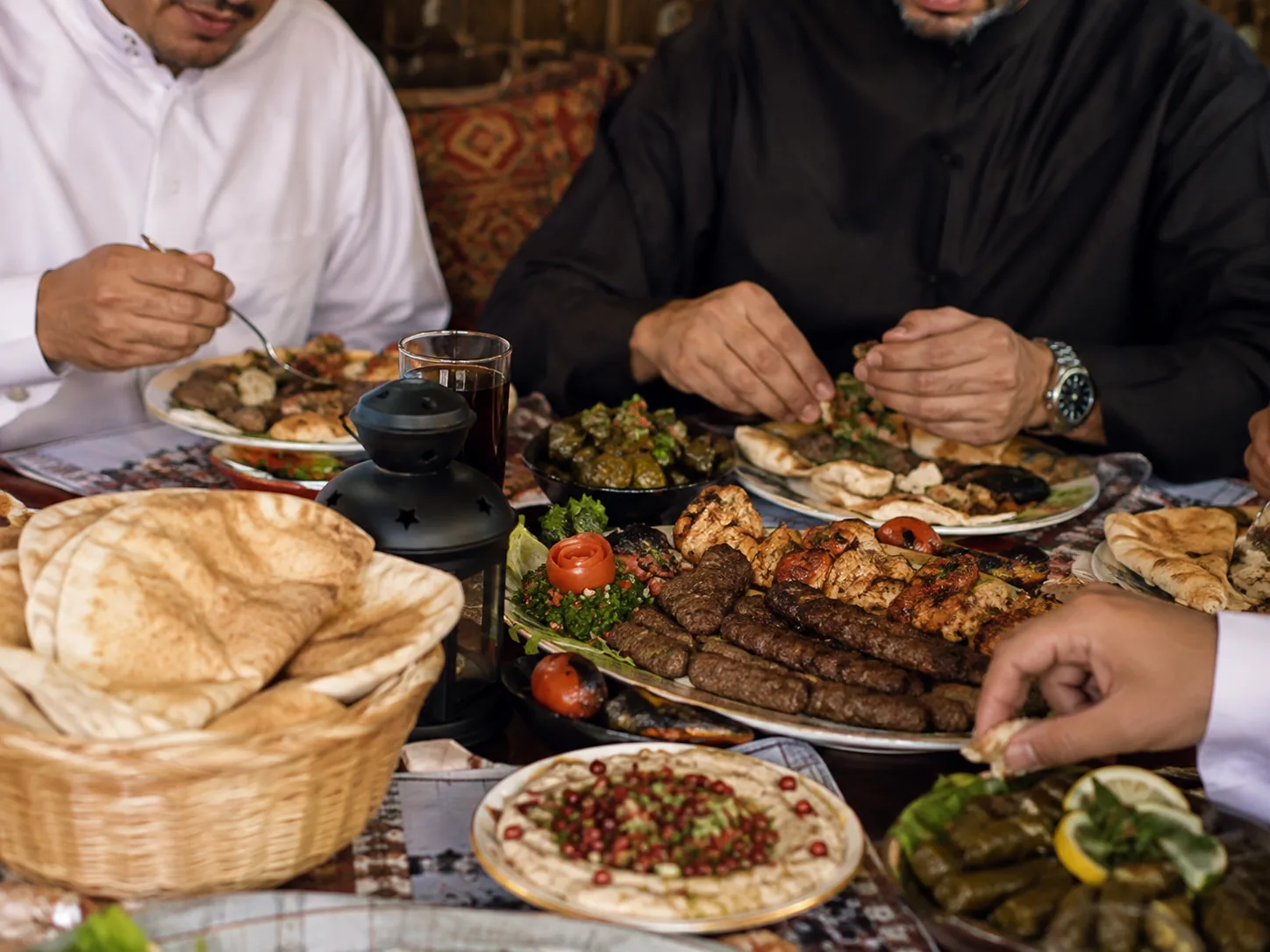 Iftar aan tafel: kebab, hummus, dolma, tabouleh en vers brood worden gedeeld bij lantaarnlicht