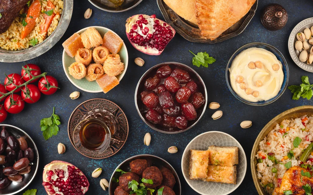 Iftar-tafel van bovenaf met dadels, thee, baklava, olijven, granaatappel en warme gerechten